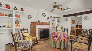 A traditional living room with a fireplace, wooden furniture, and decorative plates on shelves.