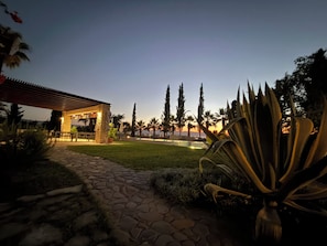 A stone pathway leading to a stone structure with a roof, surrounded by greenery and palm trees. -  Spacious 6-bedroom house in beautiful Poli Chrysochous with AC (Poli Chrysochous)