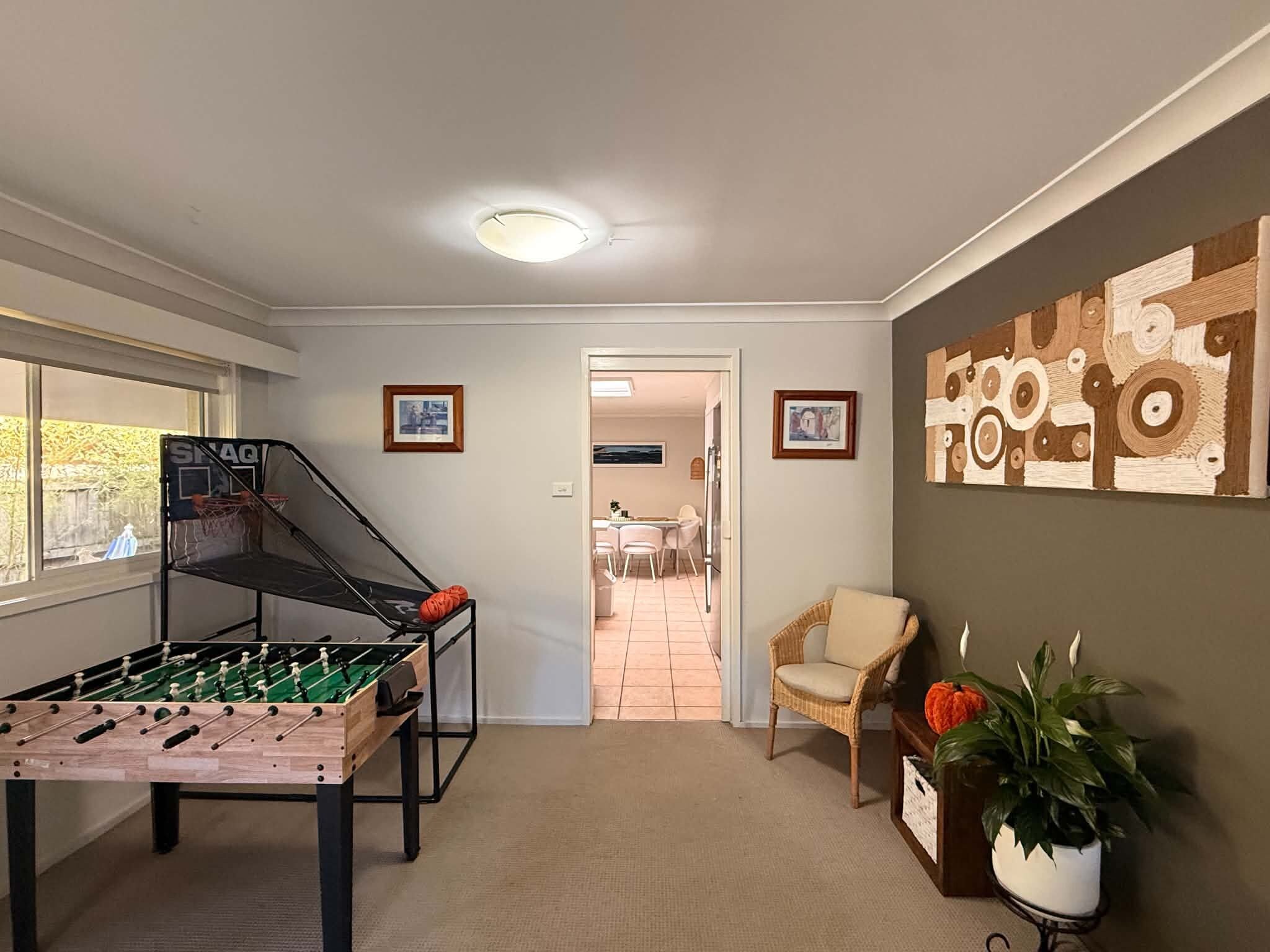 A room with a foosball table, a chair, a wall with artwork, and a door leading to another room.