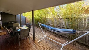 An outdoor patio with a dining table and chairs, a hammock, and a barbecue grill. - Samson Sea-clusion 3 bedroom home in Vincentia (Vincentia)