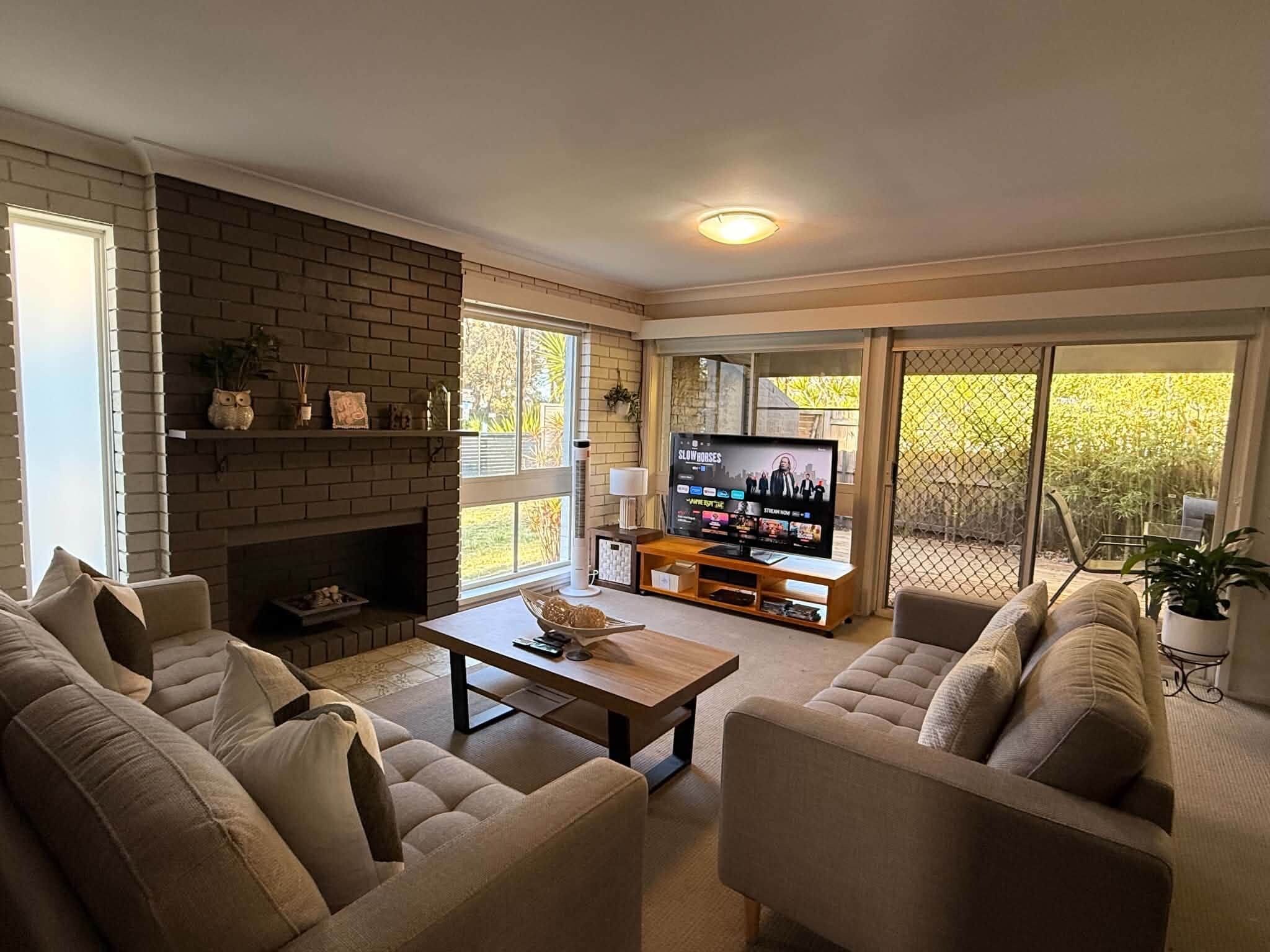 A living room with a brick fireplace, a television, and a sofa set.