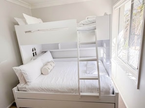 A bunk bed with a ladder, white bedding, and a window with a view of greenery. - Samson Sea-clusion 3 bedroom home in Vincentia (Vincentia)