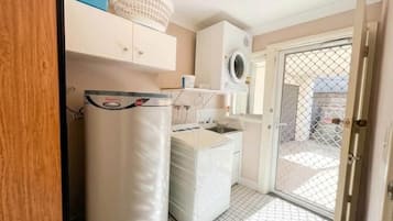 A compact kitchen with a refrigerator, washing machine, and a sink.