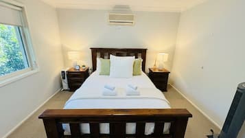 A hotel room with a large bed, bedside tables with lamps, a heater, and a window with a view.