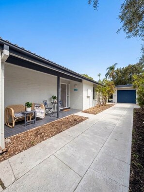 A residential property with a covered porch, outdoor seating, and a garage.