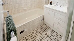A bathroom with a bathtub, a sink, and a mirror. - Samson Sea-clusion 3 bedroom home in Vincentia (Vincentia)
