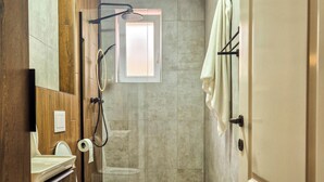 Een moderne badkamer met douche, toilet en wastafel.