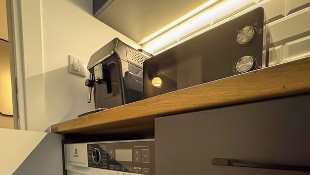 Een kleine wasruimte met een wasmachine, een droger en een magnetron op een houten aanrecht.
