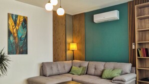 Een moderne woonkamer met een hoekbank, salontafel, lamp en een boekenkast.