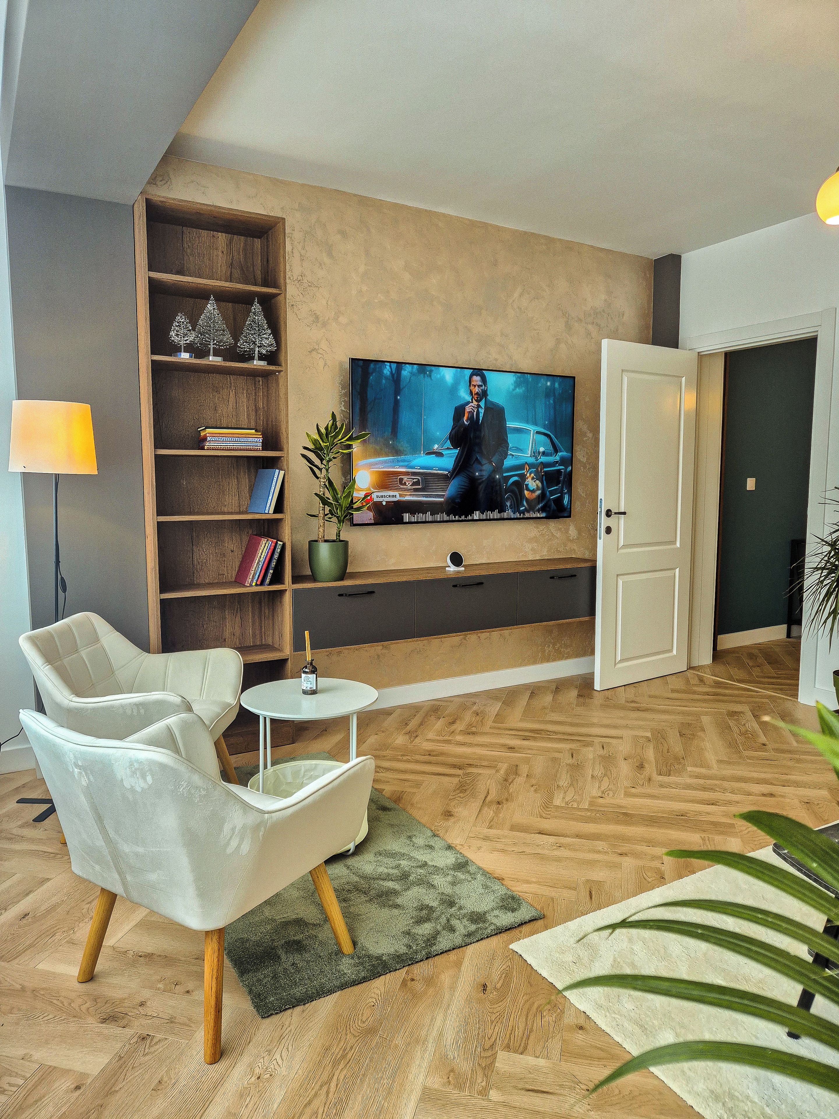 Ein modernes Wohnzimmer mit Flachbildfernseher, Bücherregal, Couchtisch und einer Sitzecke.