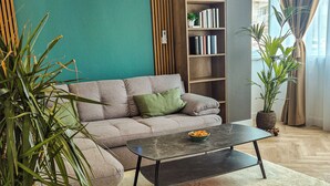 Een woonkamer met een bank, een bijzettafeltje, een boekenkast en een potplant.