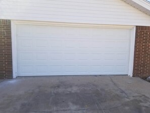 Garagem com porta branca e calçada de concreto.