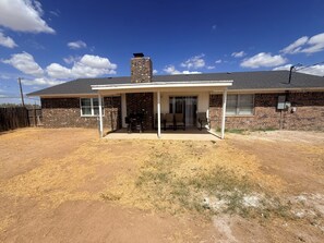 A residential house with a covered patio, brick exterior, and a chimney. - 4-bedroom Work Crew in Big Spring with AC (Big Spring)