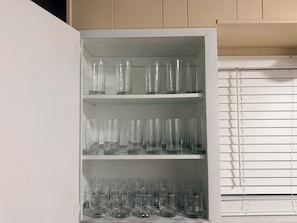 A white cabinet with multiple shelves holding clear glassware.