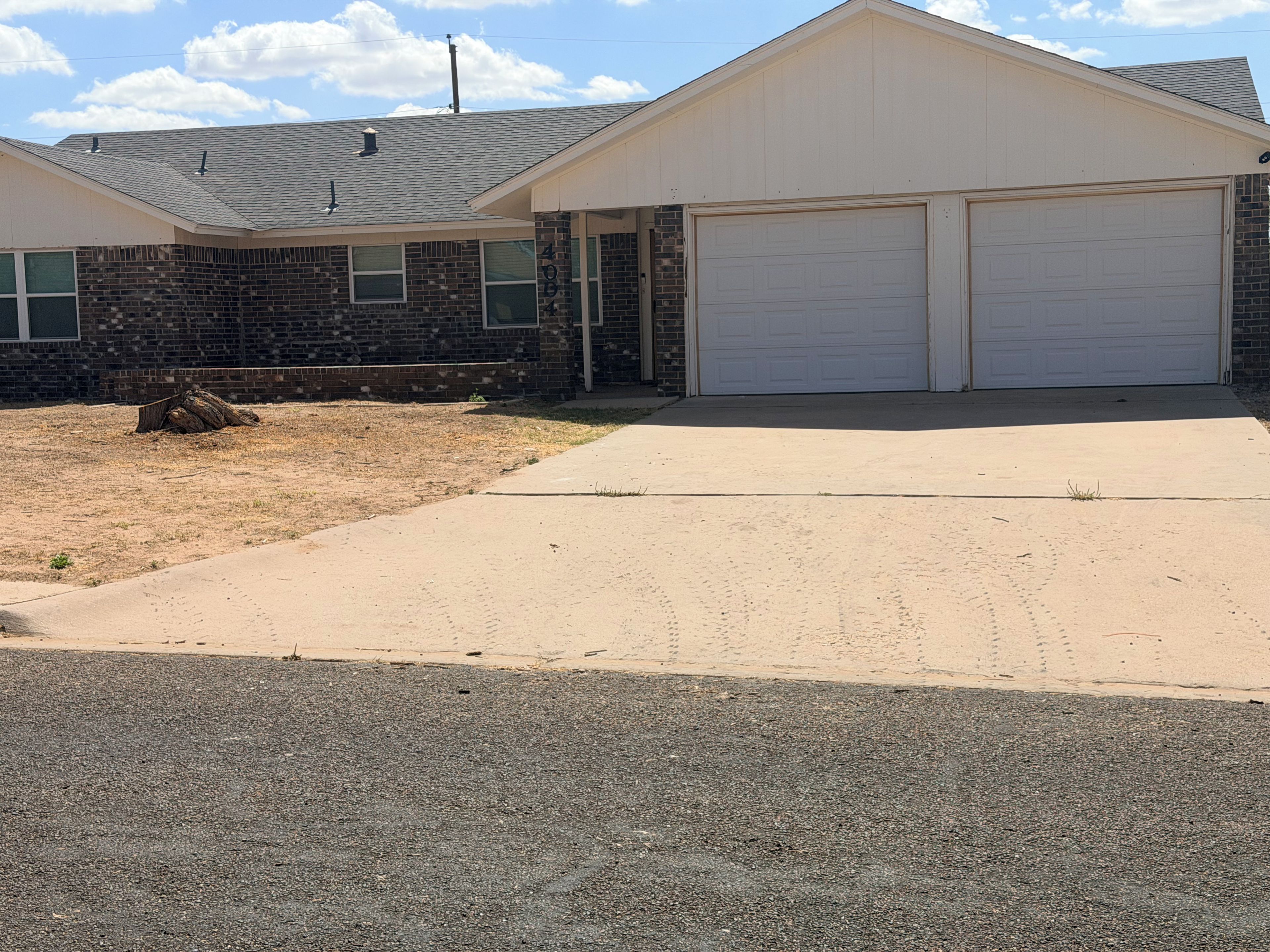 A two-story house with a garage, brick exterior, and a driveway leading to the garage.