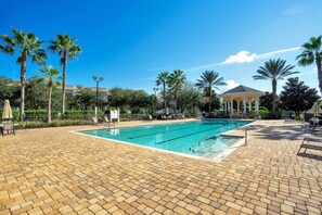 A swimming pool with a tiled deck, surrounded by palm trees and a gazebo. - Reunion Village 4BR Mickey and Moana Retreat (Kissimmee)