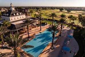 A resort with a swimming pool, lounge chairs, and a golf course in the background. - Reunion Village 4BR Mickey and Moana Retreat (Kissimmee)