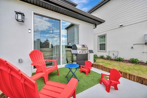 A patio with red chairs, a grill, and a small table. - Reunion Village 4BR Mickey and Moana Retreat (Kissimmee)