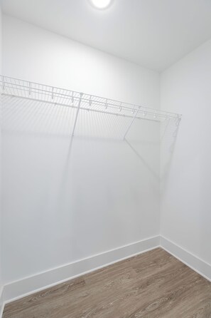 Una habitación con pared blanca, suelo de madera y un tendedero en el techo.
