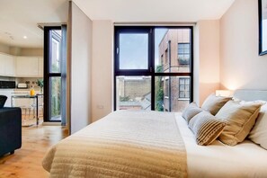 A modern bedroom with a large bed, a sofa, and a view of the city through a large window. - Spacious Apartments in Borough London Bridge by Short Stories London (London)