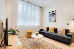 Un salon moderne avec un canapé, une table basse, un téléviseur et une plante.