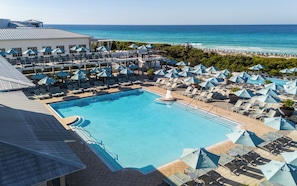 A resort pool area with multiple lounge chairs and umbrellas, a central pool, and a view of the ocean. - 17 Bluestem Ln | WaterColor, Pool, Golf Cart (Santa Rosa Beach)