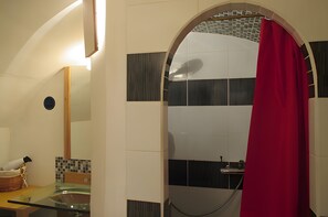 Un baño con cabina de ducha de vidrio, lavamanos, espejo y toallero.