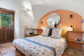 A bedroom with a bed, a mirror, a window, and a door.