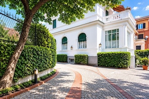 Um edifício branco com janelas em arco e um caminho de pedras que leva até ele.