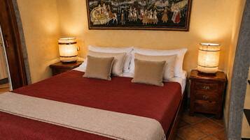 A hotel room with a large bed, two bedside tables with lamps, a painting above the bed, and a tiled floor.