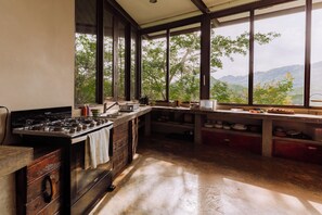 Una cocina con un ventanal grande, una estufa y diversos utensilios de cocina.