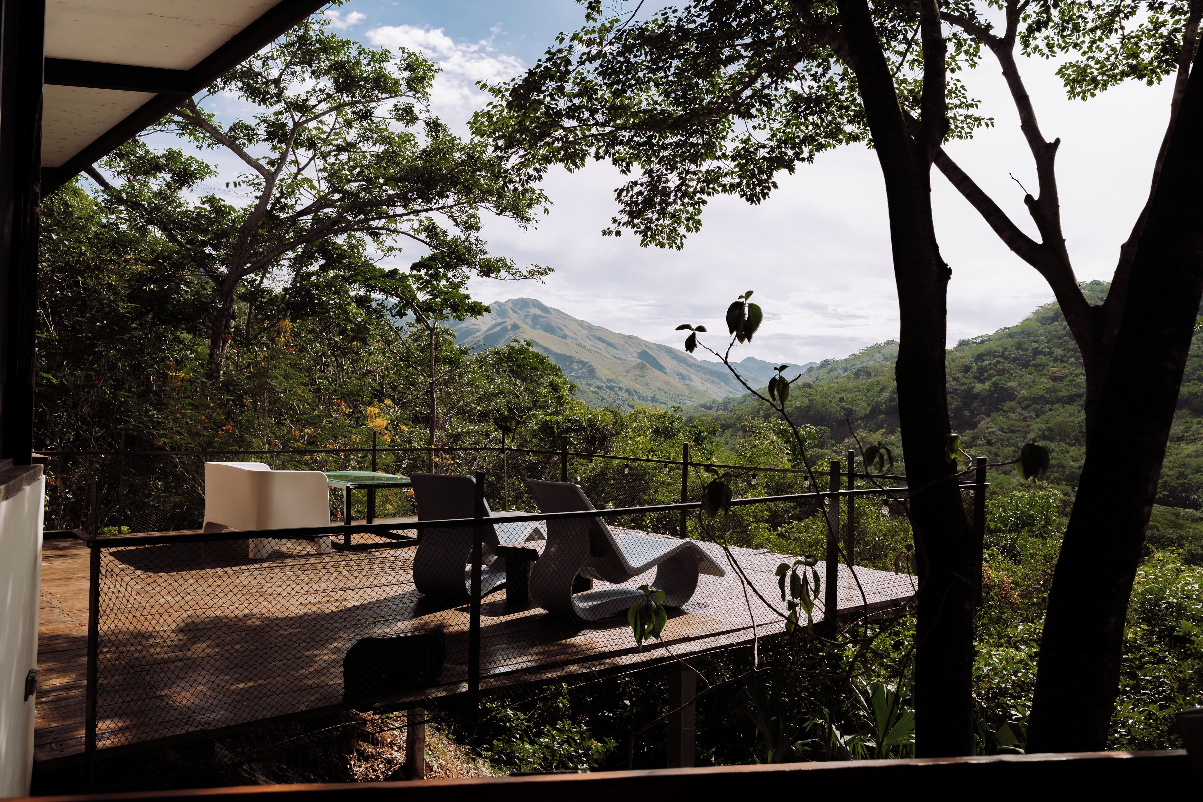 An outdoor seating area with tables and chairs, overlooking a mountainous landscape.