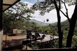 Un área de estar al aire libre con mesas y sillas, con vistas a un paisaje montañoso.