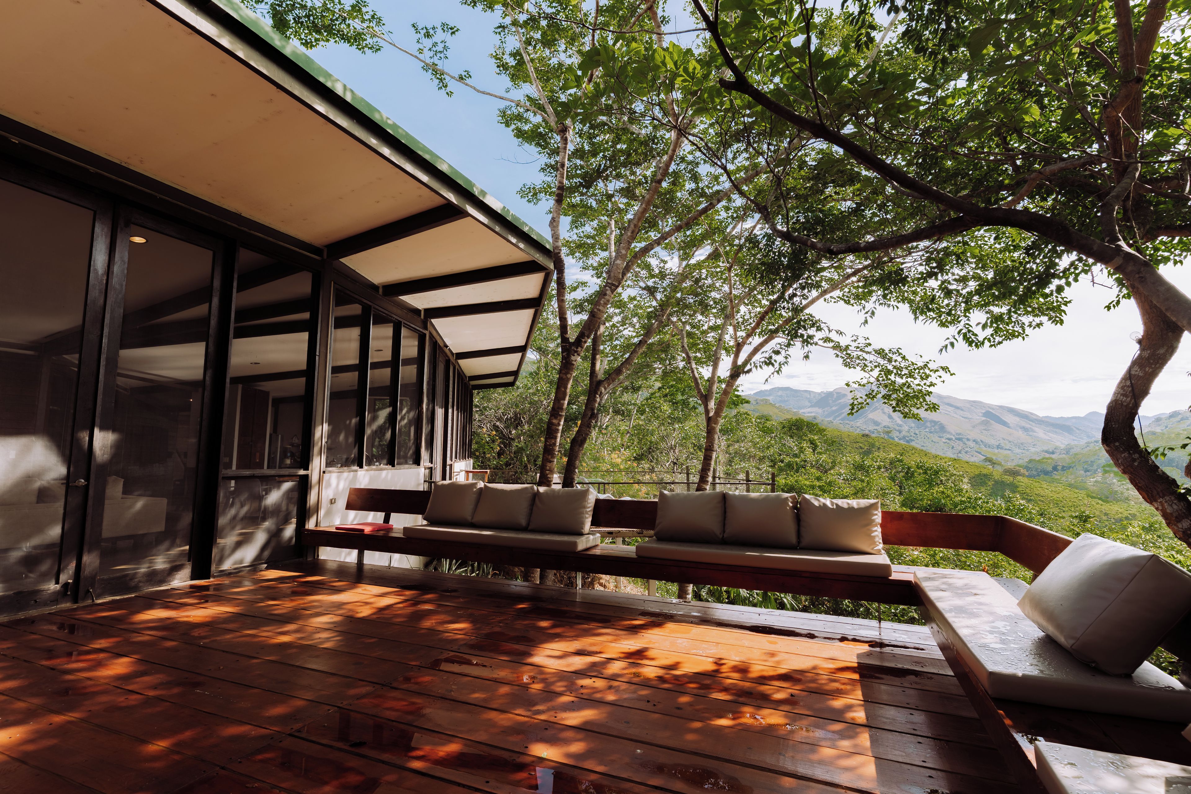 A wooden deck with outdoor seating and a view of a mountainous landscape.