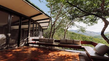 A wooden deck with outdoor seating and a view of a mountainous landscape.