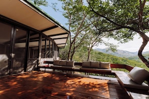 A wooden deck with outdoor seating and a view of a mountainous landscape.