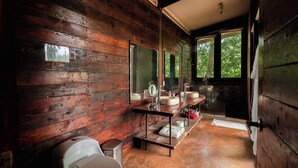 Een eenvoudige badkamer met houten details, een toilet, wastafel en douchehoek.