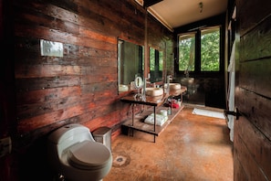 Un bagno rustico in legno con toilette, lavabo e zona doccia.