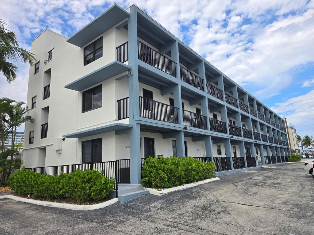 A multi-story hotel with balconies, a parking area, and a clear sky.