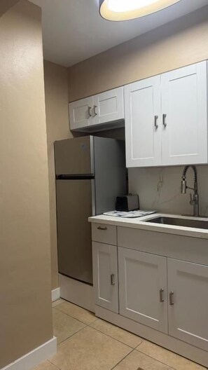 A compact kitchen with a refrigerator, a sink, and cabinets. - Free Parking Beach Condo - Beach Terrace (Hollywood)