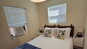 A bedroom with a bed, bedside tables, a ceiling fan, and windows. - Free Parking Beach Condo - Beach Terrace (Hollywood)