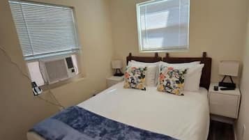 A bedroom with a bed, bedside tables, a ceiling fan, and windows.