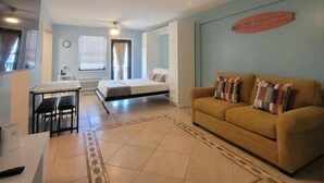 A modern living room with a sofa, a dining table, and a ceiling fan. - Free Parking Beach Condo - Beach Terrace (Hollywood)