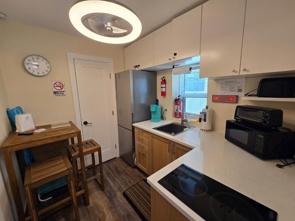 A compact kitchen with a microwave, sink, and wooden cabinets.