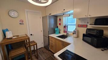 A compact kitchen with a microwave, sink, and wooden cabinets.