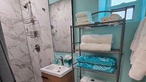 A bathroom with a shower, toilet, sink, and a towel rack with towels. - Free Parking Beach Condo - Beach Terrace (Hollywood)