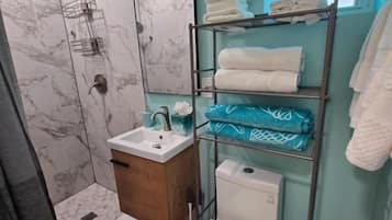 A bathroom with a shower, toilet, sink, and a towel rack with towels.