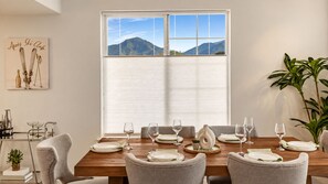 A dining room with a large window, a table set for six, and a ski-themed artwork on the wall. - 3BR Modern Retreat | Hot Tub | Near 4 Ski Resorts (South Salt Lake)