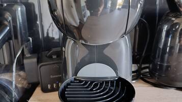 Un plan de travail de cuisine avec une machine à café, une bouilloire et un moulin à café.