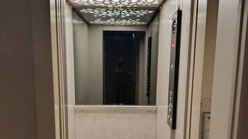 L’intérieur d’un ascenseur, avec un plafond réfléchissant et un panneau de commande situé à droite.